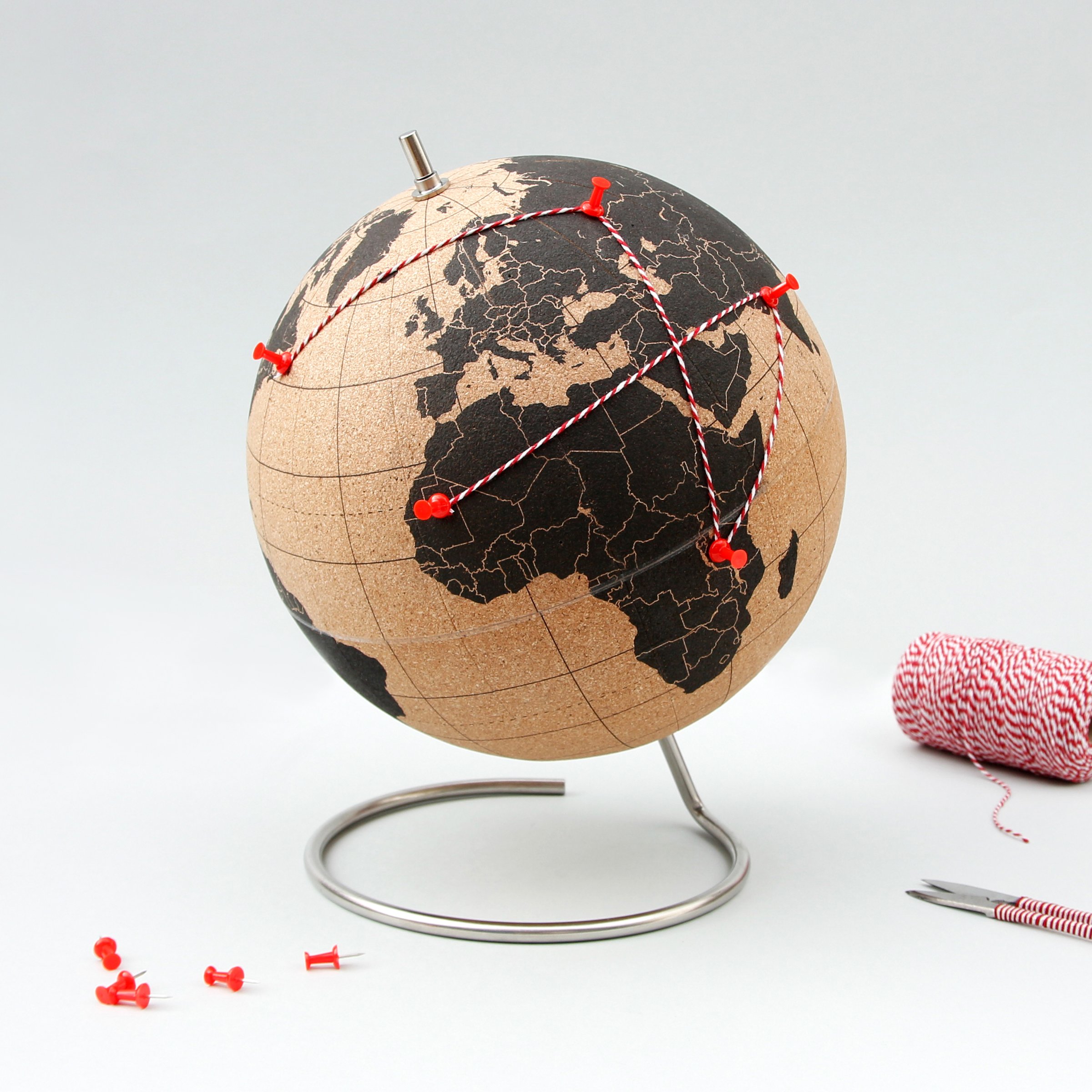 Cork globe with red pins and string showing global connections
